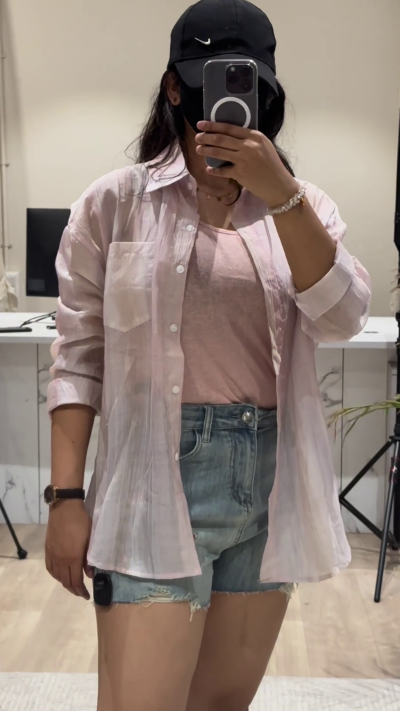 Casual Layered Outfit: Pink Button-Down Shirt, Tank Top, and Denim Shorts - Photo 1