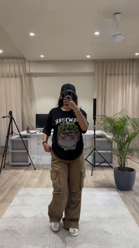Urban Chic Outfit: White Graphic Tee, Rust Cargo Pants, and Black Cap - Photo 2