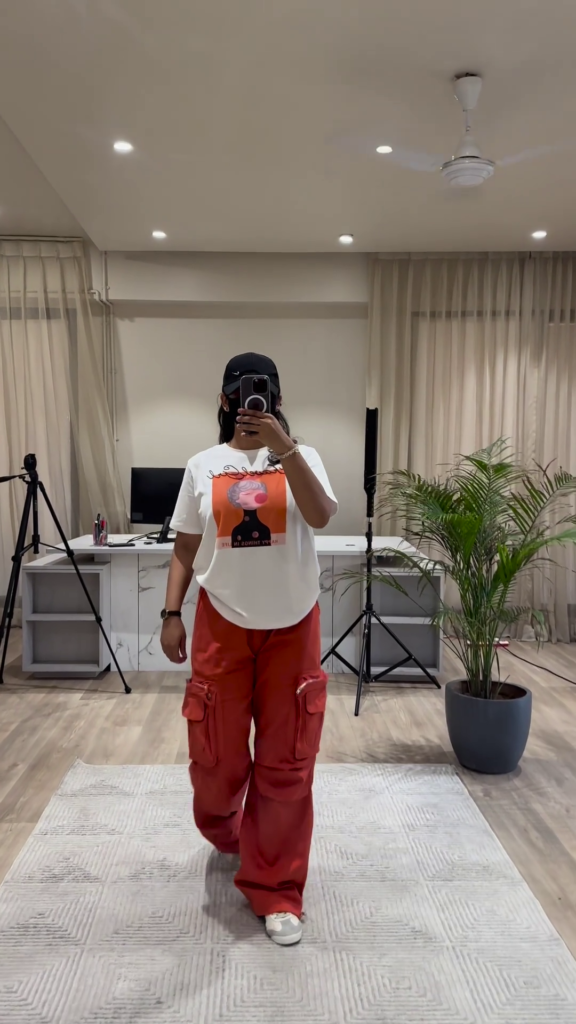 Urban Chic Outfit: White Graphic Tee, Rust Cargo Pants, and Black Cap - Photo 1